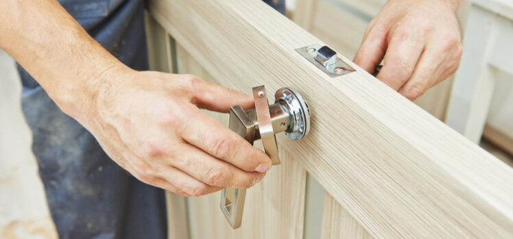 Technician fitting a lock set into a new wooden door